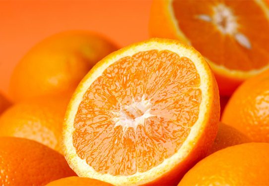 Close up photo of oranges with two oranges sliced in half.